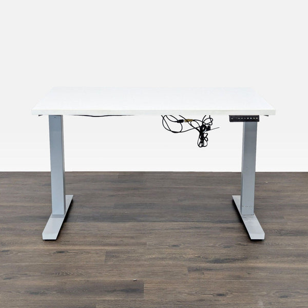 White electric standing desk by Reperch with silver legs, shown from the front against a wood floor.  