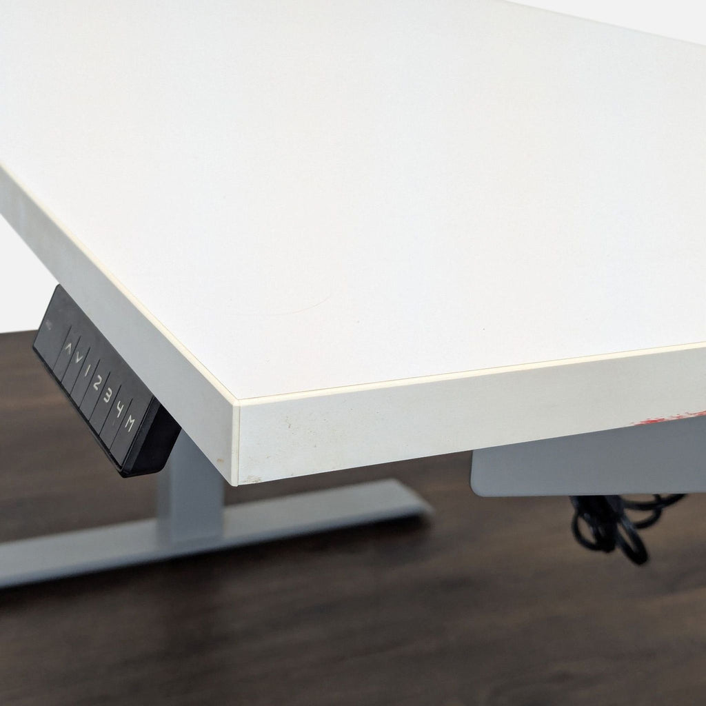 2. Close-up of the white Reperch desk corner, showing its edge and electronic height control panel underneath.