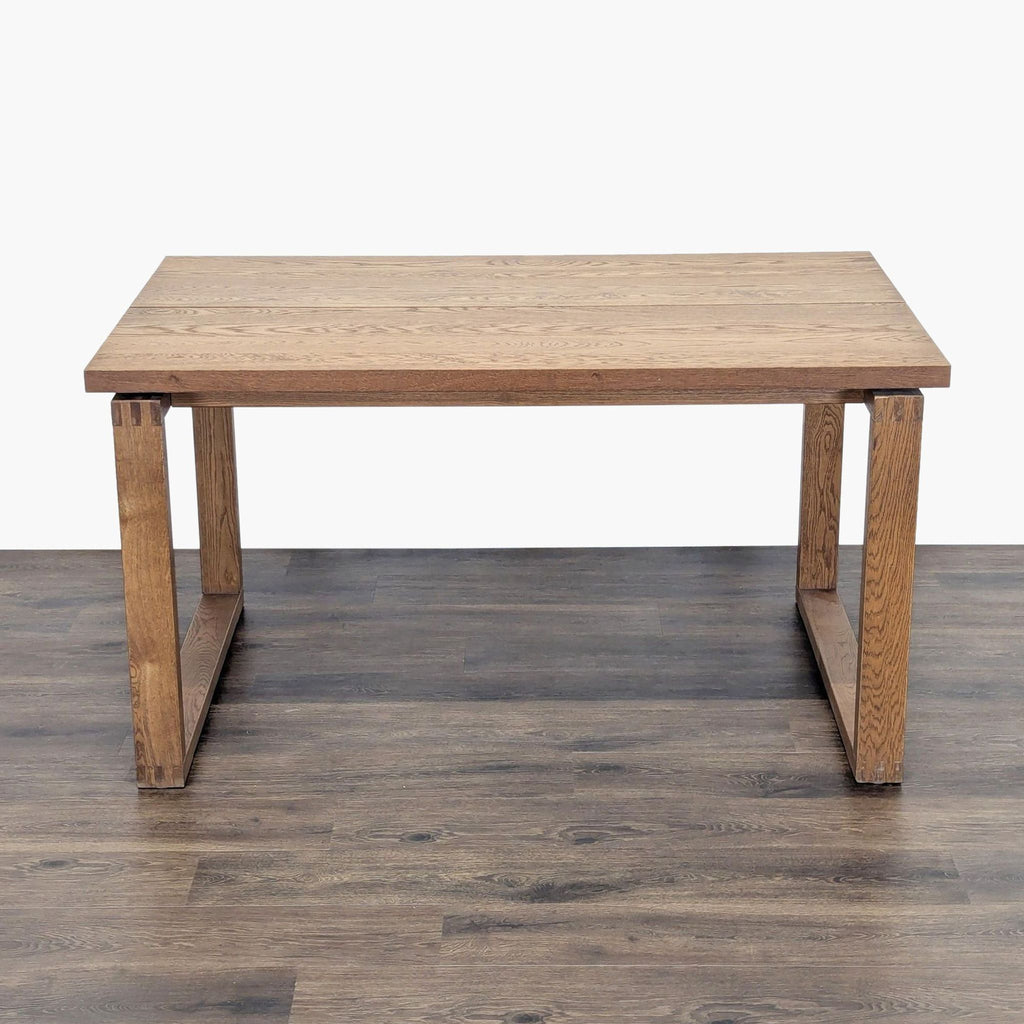 3. Simple oak veneer dining table by IKEA, plank-style top with sturdy, box-frame legs, on wood flooring.