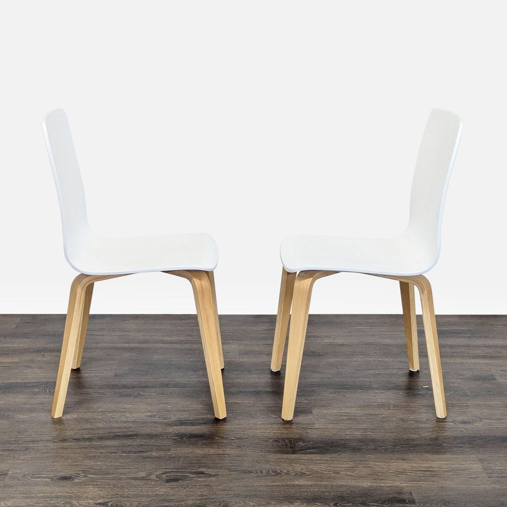 3. Side view of two Anthropologie dining chairs, clear lacquer finish, white seats, wood legs, facing each other.