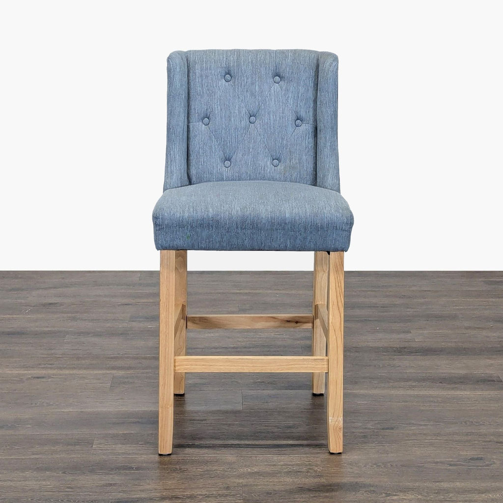 1. Blue upholstered Noble House Home stool with button-tufted back and wooden legs, placed on a dark floor.