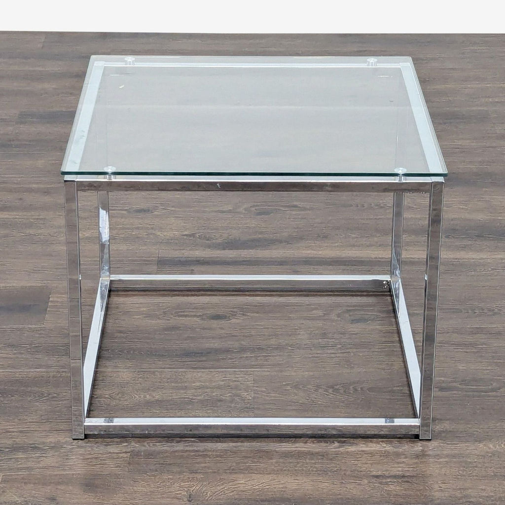 3. Front view of a Reperch end table featuring a clear glass top and a minimalist chrome-finished metal frame.