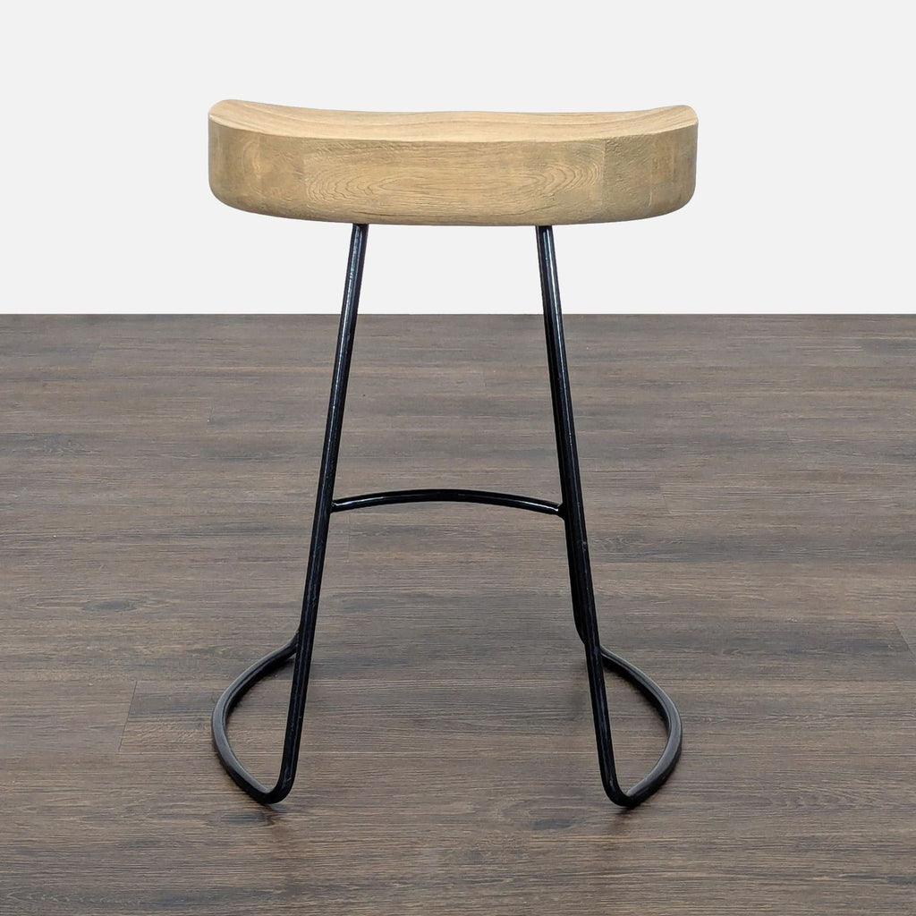 3. Back view of a Restoration Hardware stool featuring a contoured wood seat and sleek black metal base.