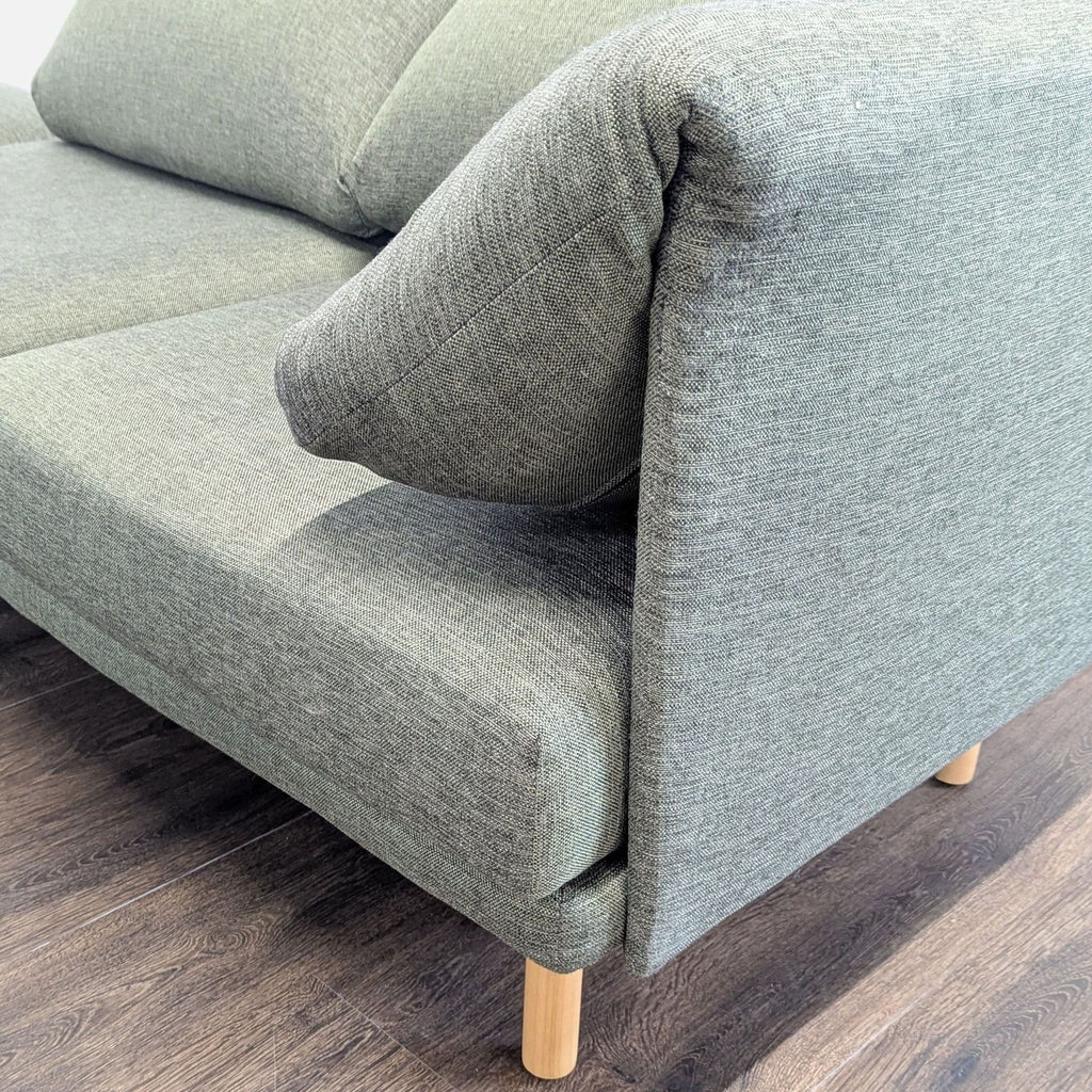 1. Close-up of a Burrow sectional sofa showing green upholstery and wooden legs on a dark floor.  