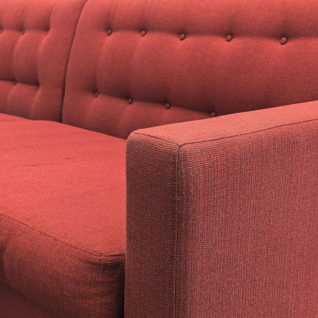 Close-up of the tufted red fabric and armrest on a Room and Board 3-seat sofa, showing texture and detail.  