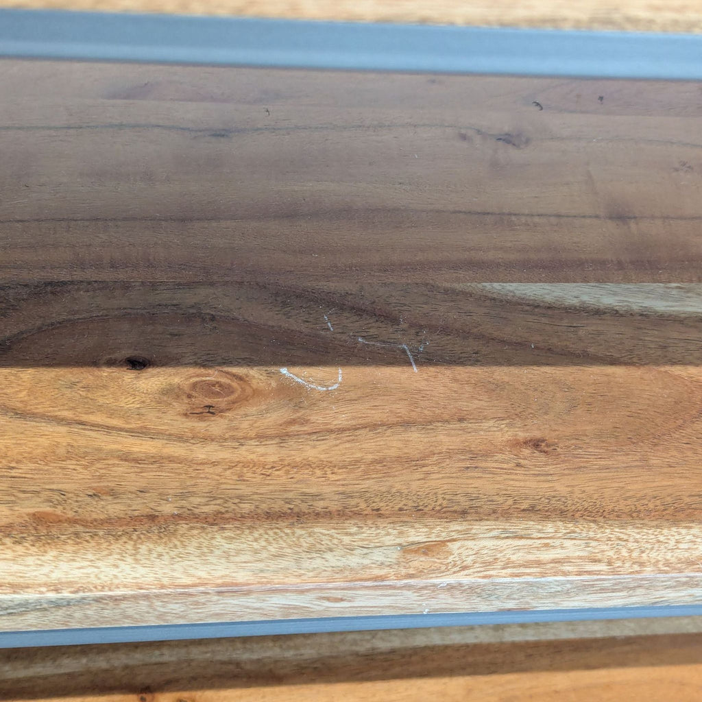 3. Close-up of acacia wood shelves on CB2 entertainment center, showing natural grain, knots, and light scratches.