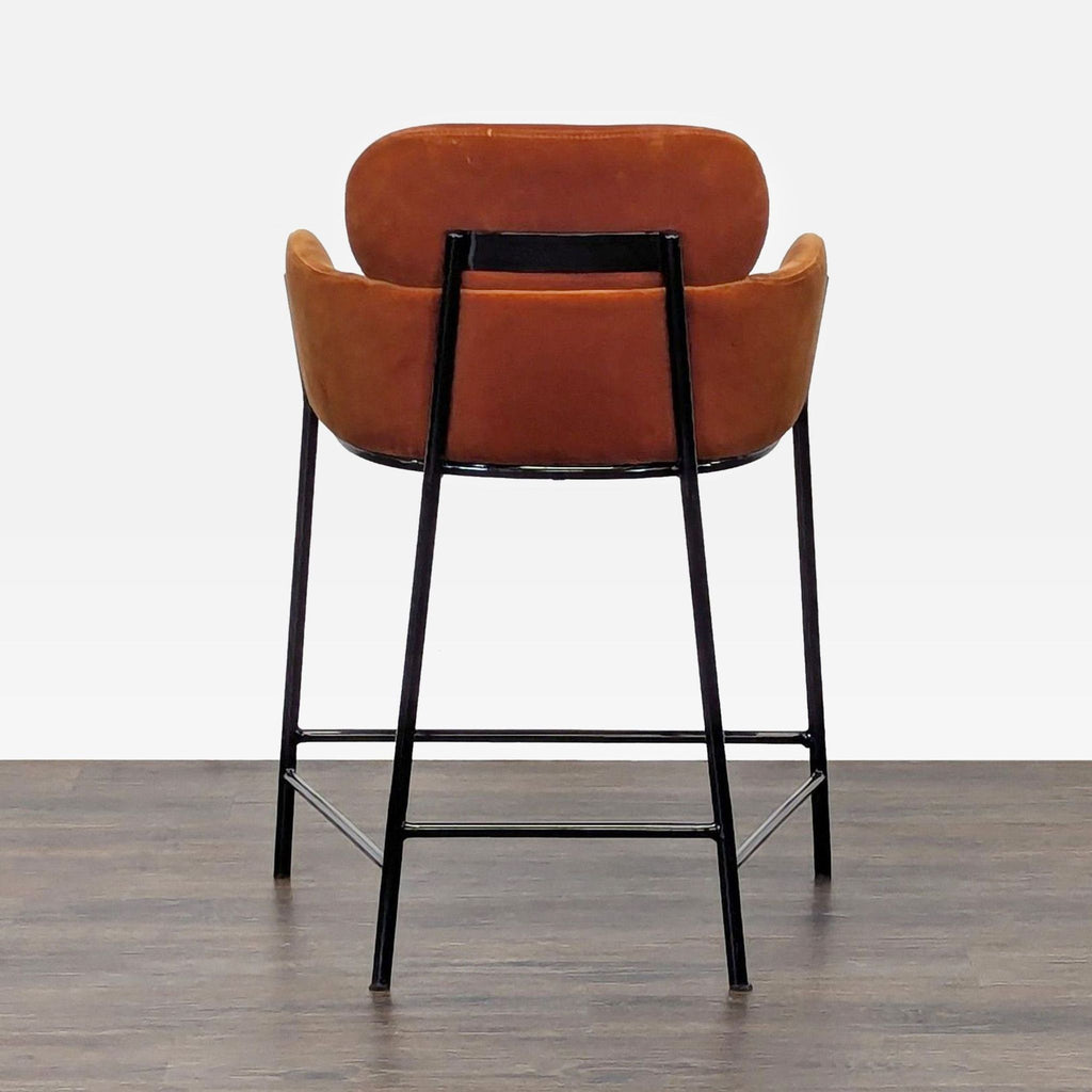 2. Rear view of a modern CB2 velvet stool, showing curved back and powder-coated black iron frame.  
