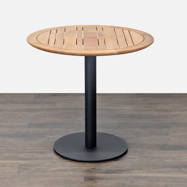 1. Ventana round table with a wood slatted top and black metal base, shown on a wood floor.