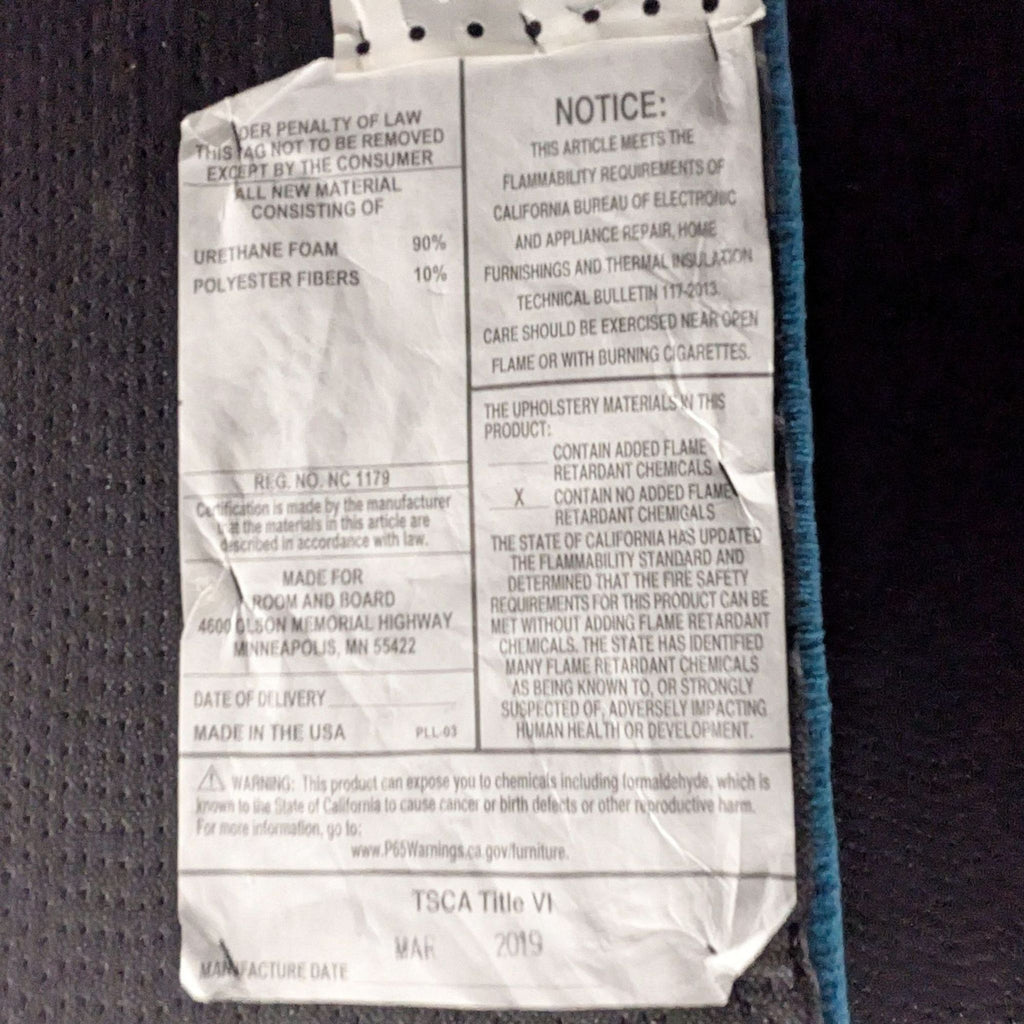 1. Close-up of a Room & Board frame tag listing materials, safety, and manufacturing details in black text.