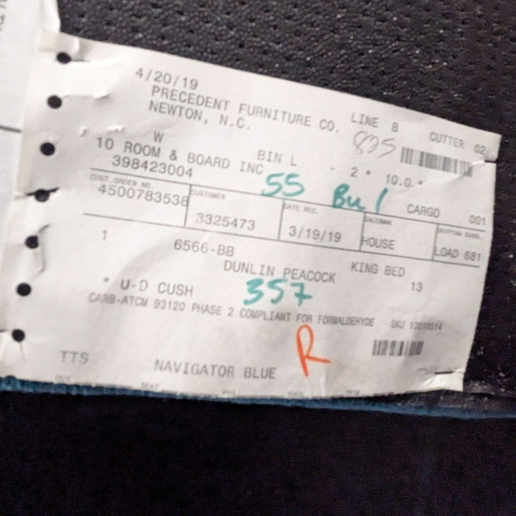 3. Shipping and inventory tag showing Room & Board brand, frame item details, and handwritten notes attached to upholstery.