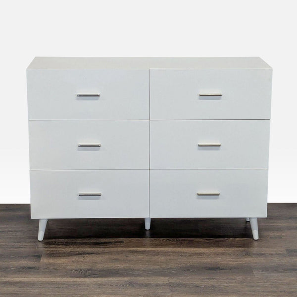 Front view of a modern white West Elm dresser with six drawers and sleek metal handles on wooden floor.