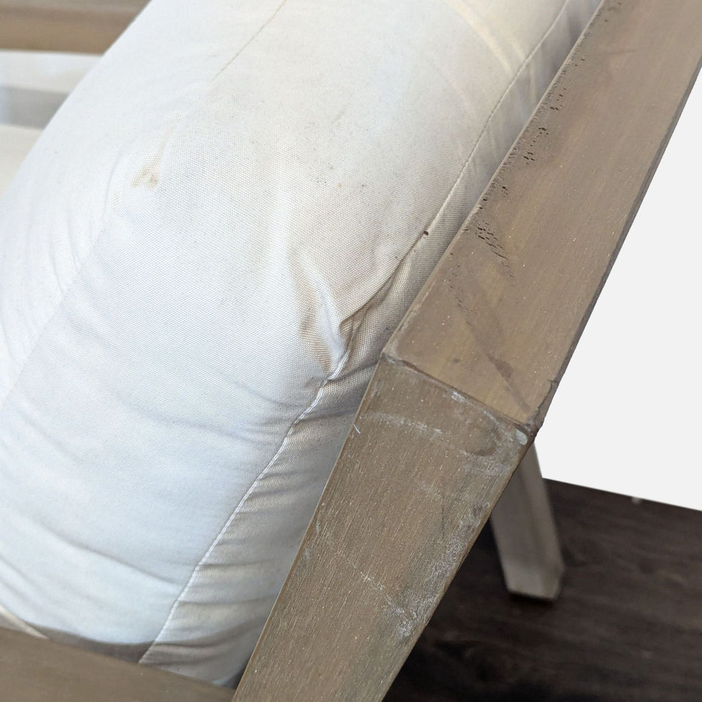 Close-up of the Pottery Barn chair's backrest showing white cushion and wood armrest with visible scratches.  