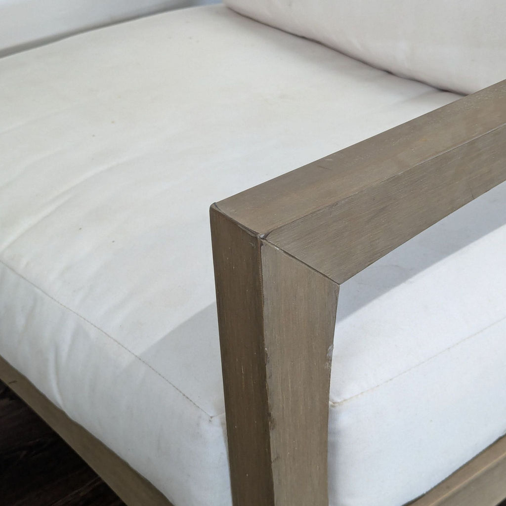 Detailed view of a Pottery Barn chair's light wood armrest and white seat cushion, highlighting seat texture.