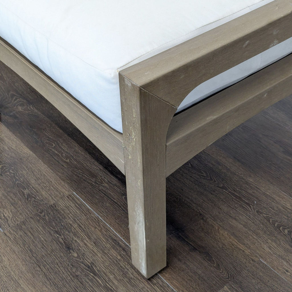 3. Close-up of a Pottery Barn ottoman corner showing detailed light wood construction and white fabric cushion.