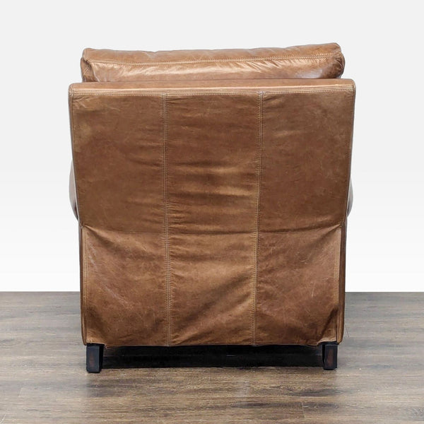1. Rear view of a Pottery Barn lounge chair featuring brown leather upholstery and wooden legs.  