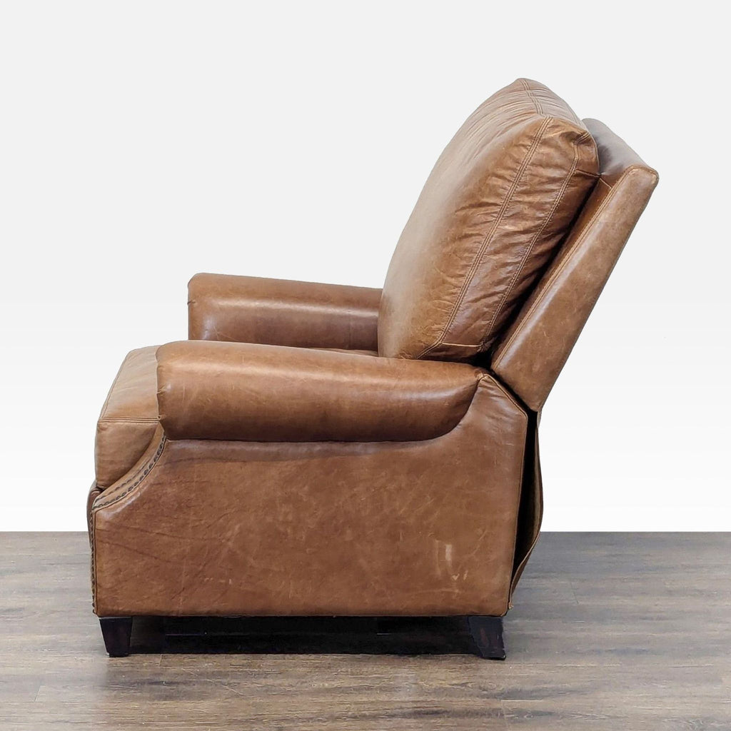 2. Side profile of a Pottery Barn brown leather lounge chair showing plush cushioning and sturdy arms.  