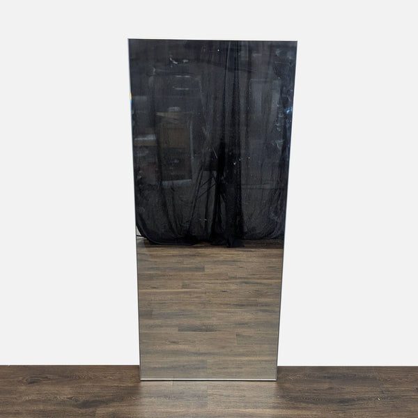 1. Tall CB2 mirror with a sleek metal frame, reflecting a room with a dark curtain and wooden floor.