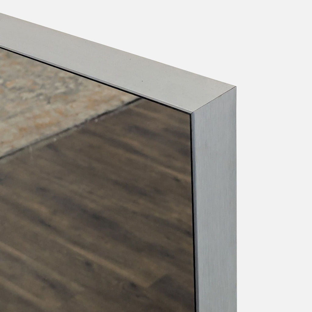 2. Close-up of the CB2 metal-framed mirror, highlighting the brushed silver edge and corner.