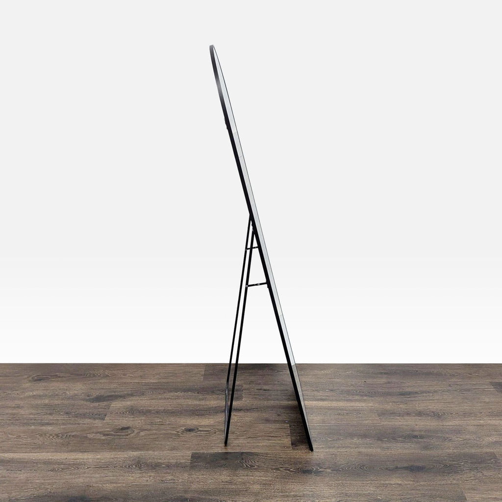 2. Side view of the Reperch mirror, showing its thin frame and fold-out stand on a wooden floor.