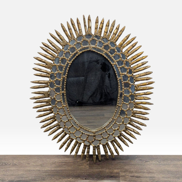 1. Reperch oval giltwood wall mirror with a sunburst design and decorative frame, displayed on a wooden floor.