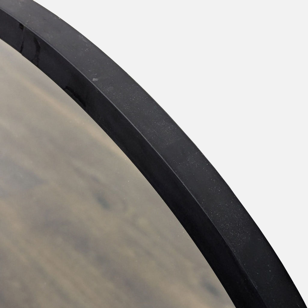 Close-up of the black-framed edge of the Umbra round mirror, showing its smooth finish and minimal design.  