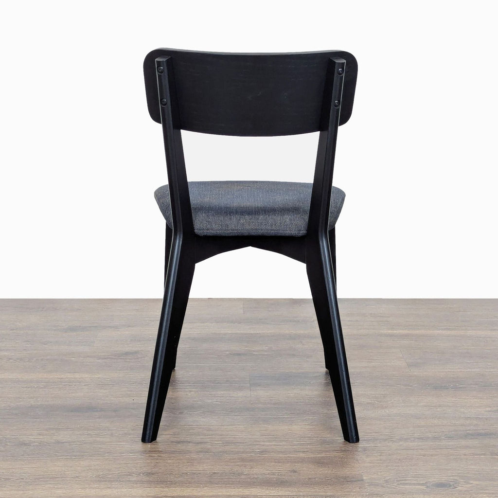 2. Rear view of an Ikea dining chair, showing the curved black wooden backrest and padded seat.