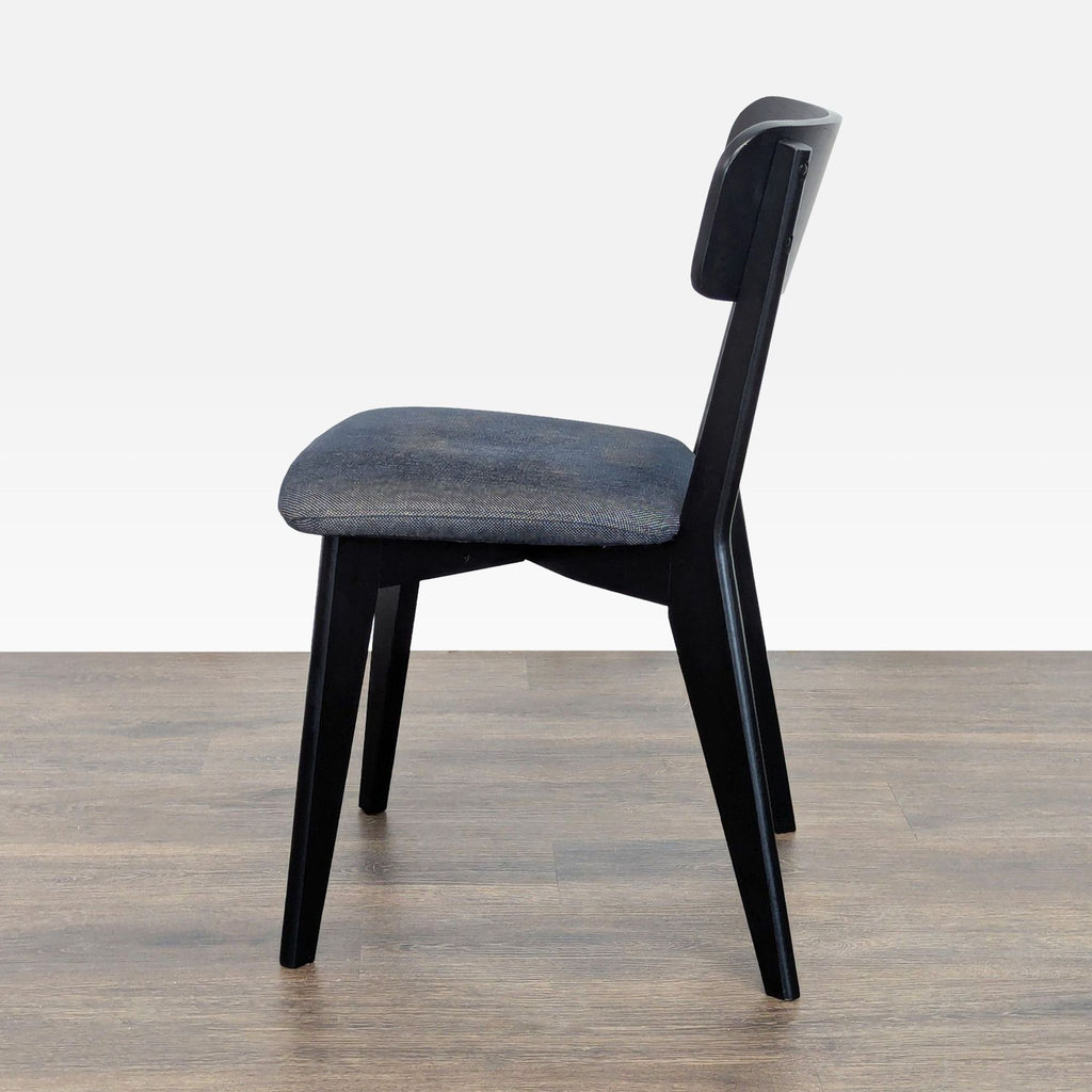3. Side profile of an Ikea dining chair featuring a black wooden frame and a dark upholstered cushion.
