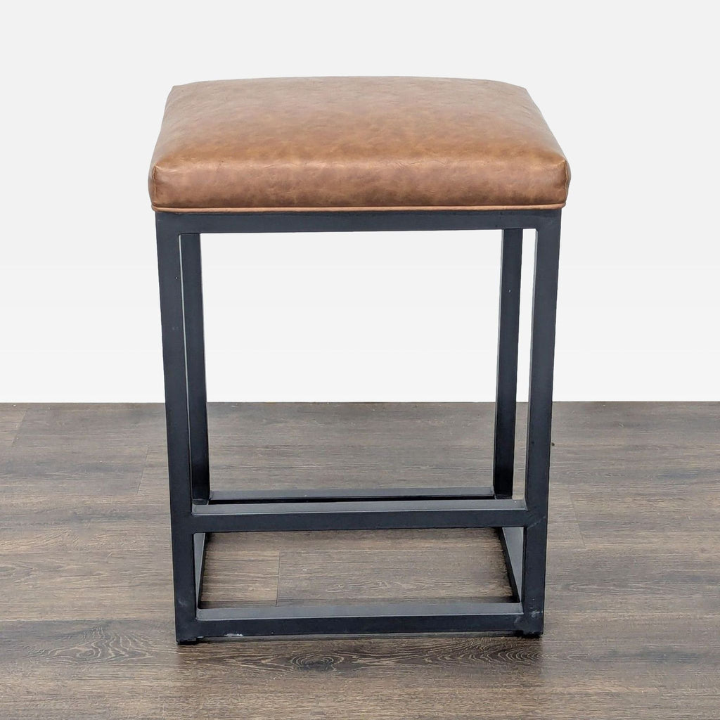 1. Bluefyn stool with a black metal frame, built-in footrest, and cushioned faux leather seat, front angle view.  