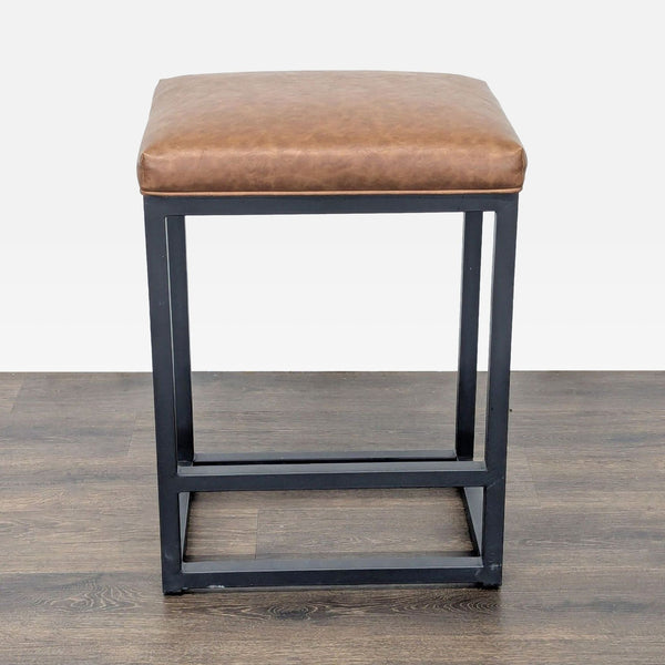 1. Bluefyn stool with a black metal frame, built-in footrest, and cushioned faux leather seat, front angle view.  