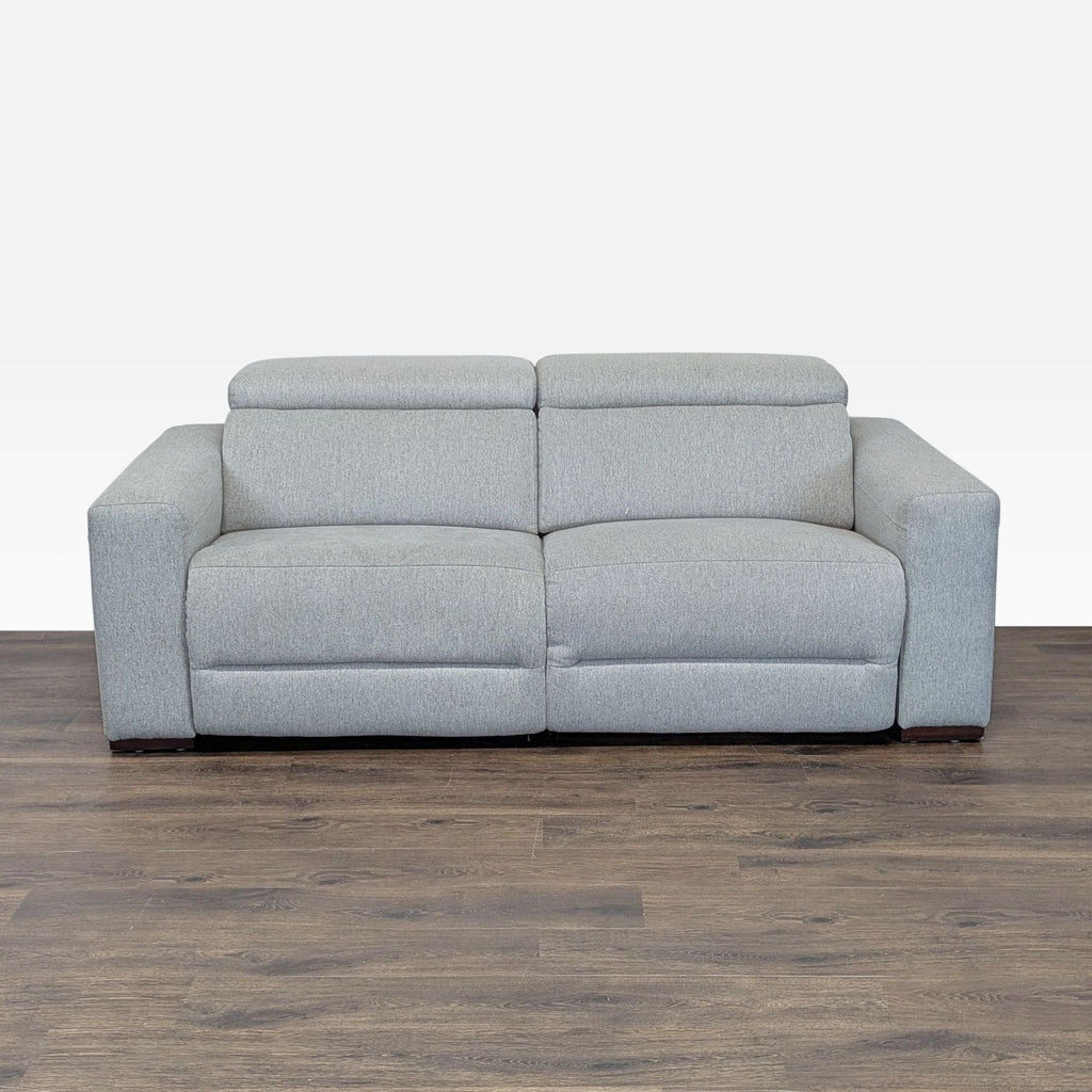 1. Light gray Macy’s sofa with wide arms, adjustable headrests, and a modern design displayed on wood flooring.