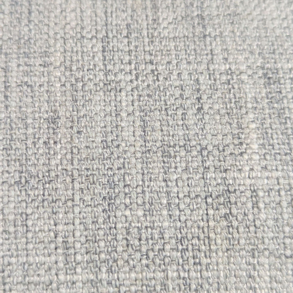 Close-up of light gray woven fabric upholstery, showing the texture of a dining chair seat.  