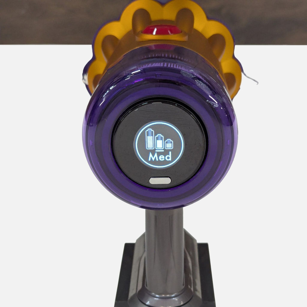 Digital display on top of Dyson stick vacuum shows battery status and cleaning mode setting.