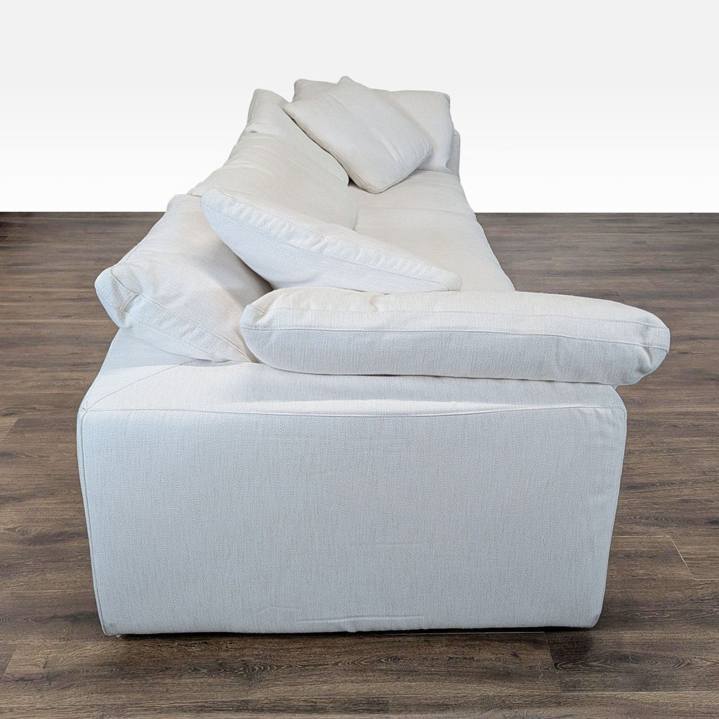 Side view of a spacious Restoration Hardware 3-seat sofa in soft white fabric with plush cushions.