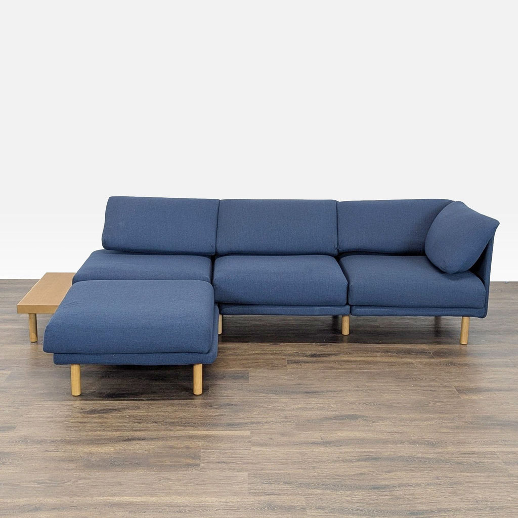 Modern blue Burrow sectional with light wood legs and a built-in side table, shown from the front.