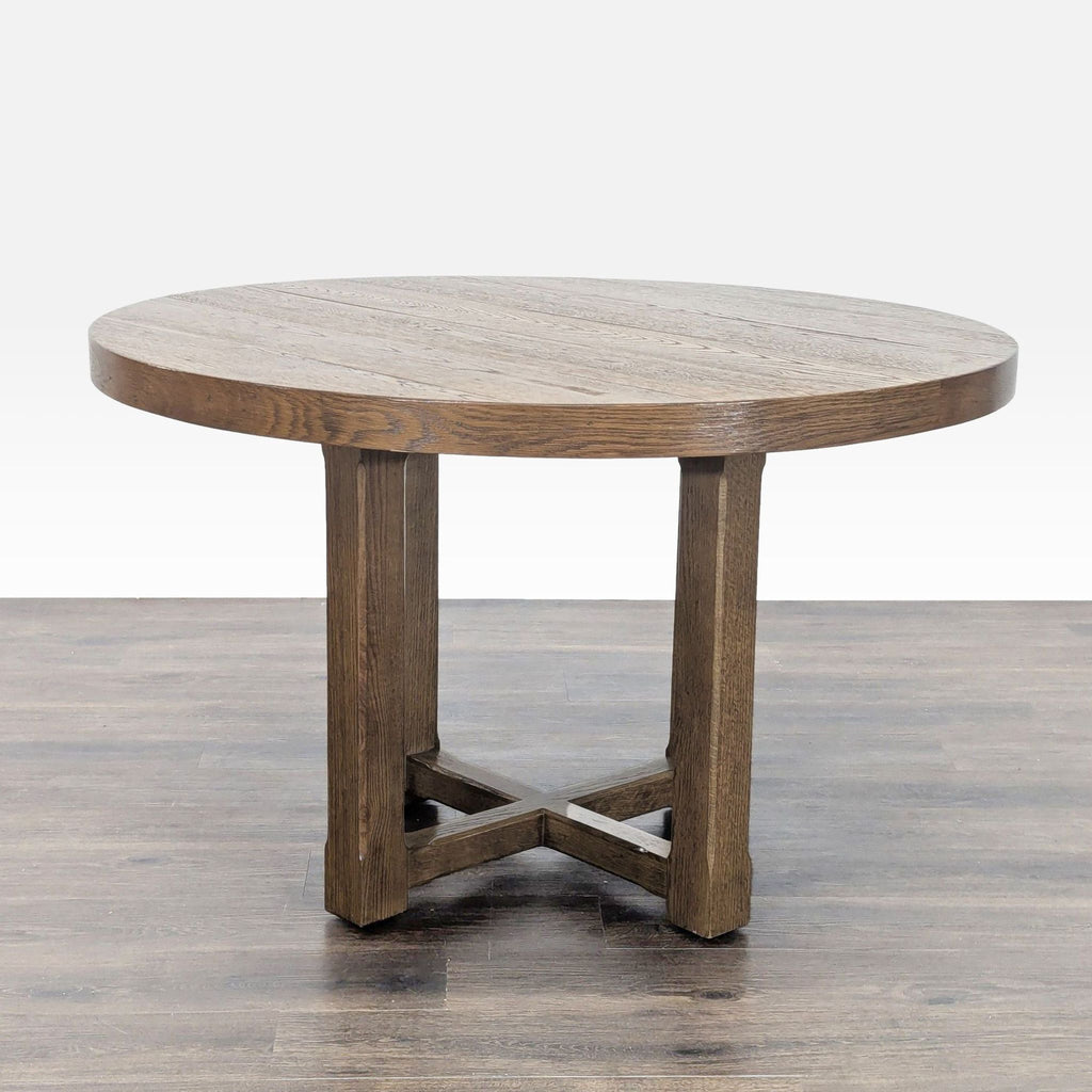 1. Round Restoration Hardware dining table in oak veneer with visible wood grain and a sturdy cross-base design.