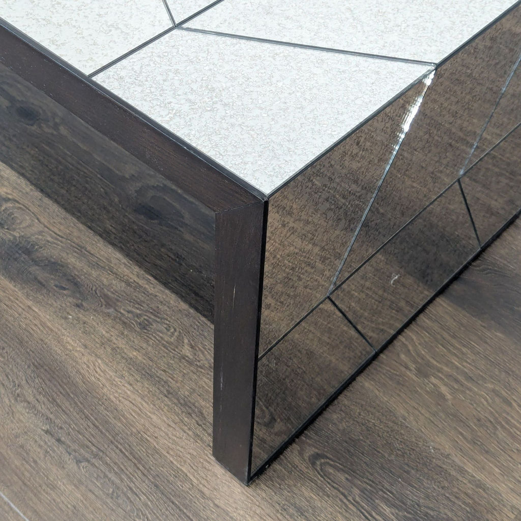 Close-up of a modern West Elm bench corner with geometric mirrored and tiled surface on wood flooring.