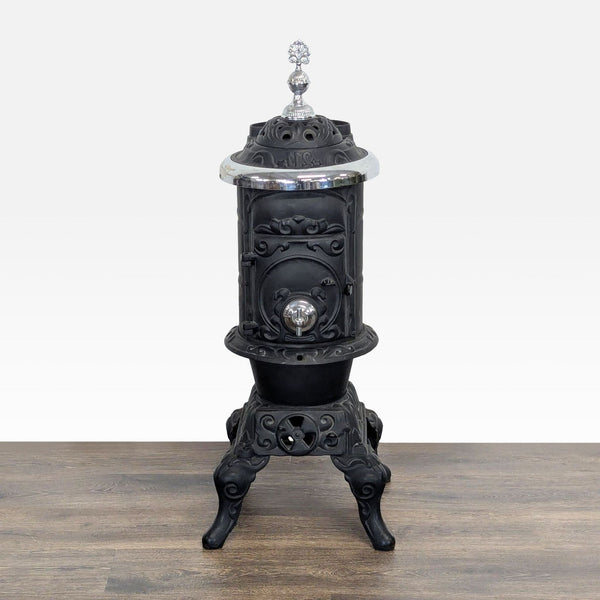 Antique cast iron parlor stove by Reperch with ornate details, silver accents, and decorative finial on top.  