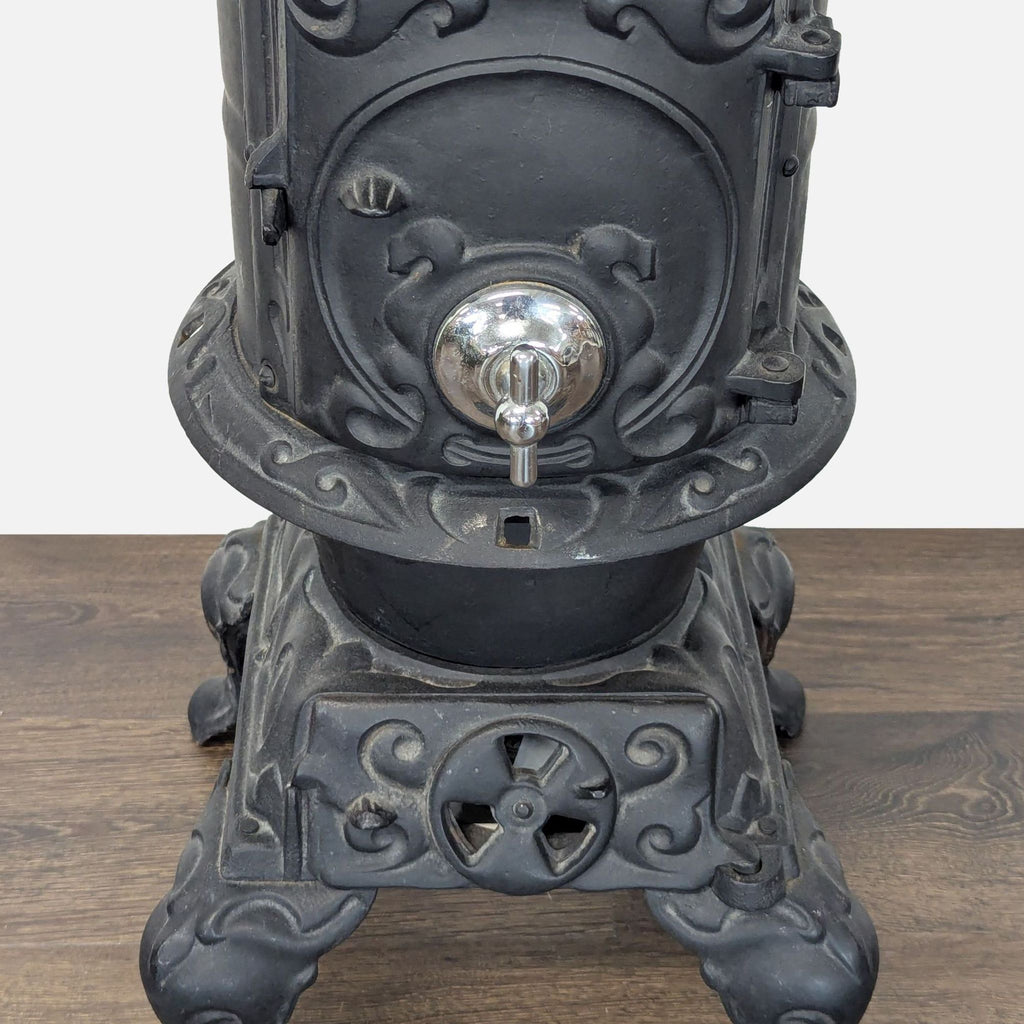 Detailed view of the elegant silver handle and ornate scrollwork on the Reperch cast iron stove’s front door.