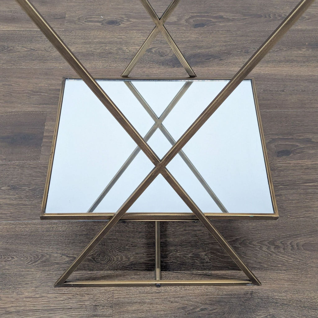 3. Close-up of lower shelf and X-frame detail on a Reperch gold and glass two-tiered accent table.
