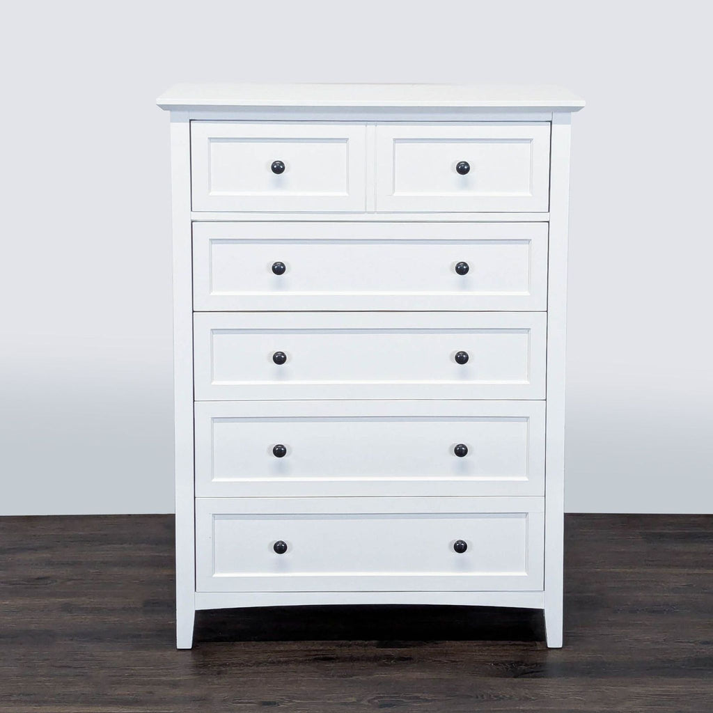1. White Modus dresser with five drawers and black knobs, shown on a dark wood floor, front view.