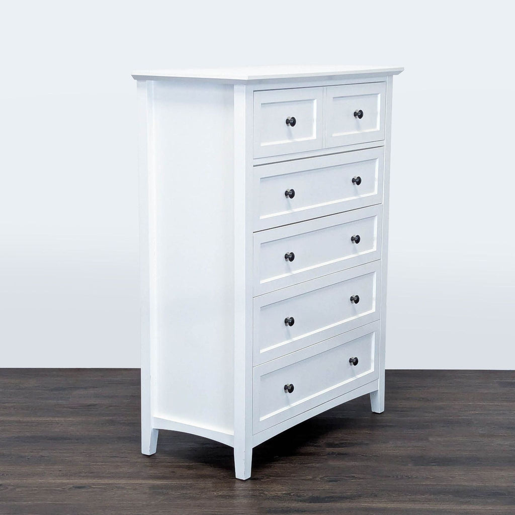 3. Angled view of Modus white dresser with five drawers, black knobs, and a simple, modern look.