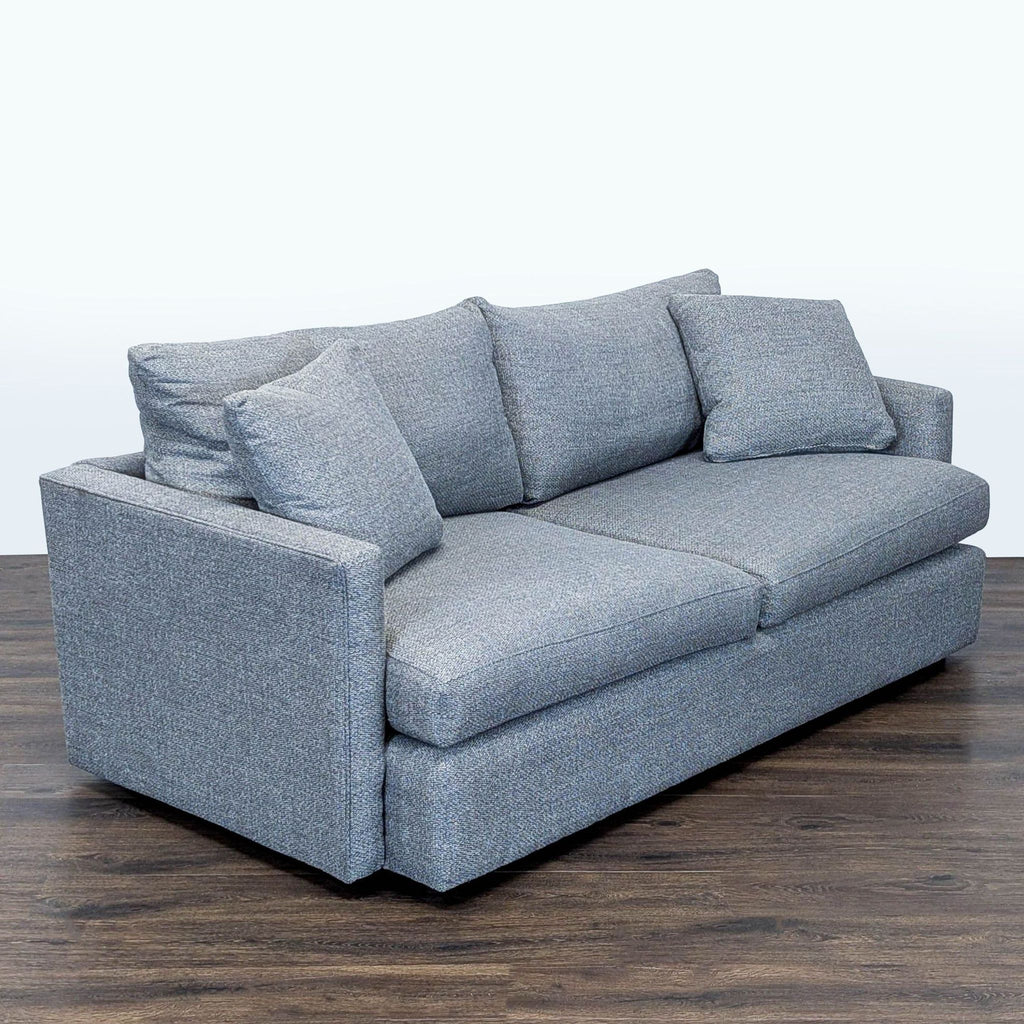 2. Angled side view of Crate and Barrel 3-seater gray sofa with soft cushions on a wood floor.