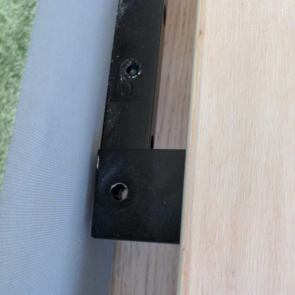 Close-up of Poly and Bark bed frame corner, showing fabric, wooden slat, and sturdy metal bracket.
