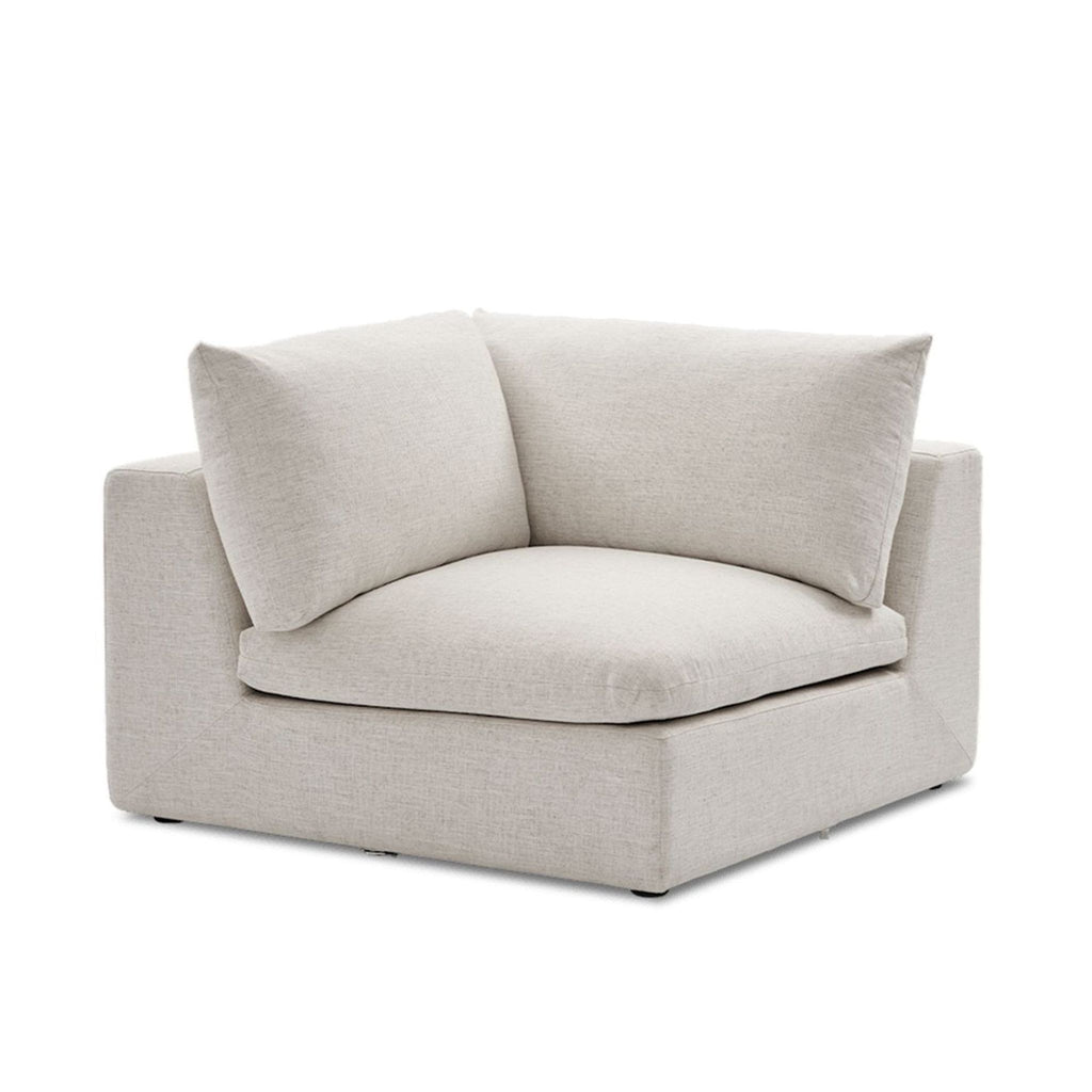 Castlery corner section seat in light beige fabric with wide cushioned seat and plush back pillows, modern style.  