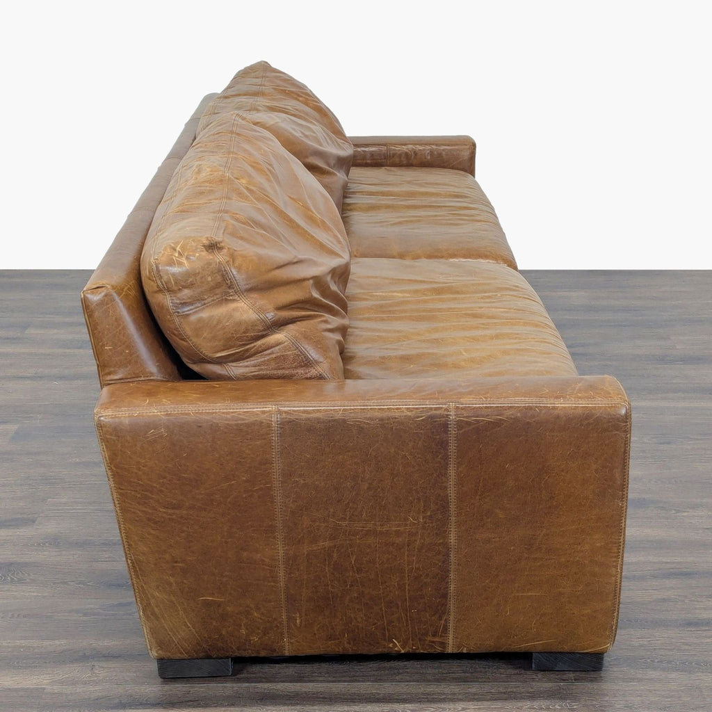 2. Side view of a genuine brown leather 3-seat sofa by Restoration Hardware, showing modern lines and sturdy arms.
