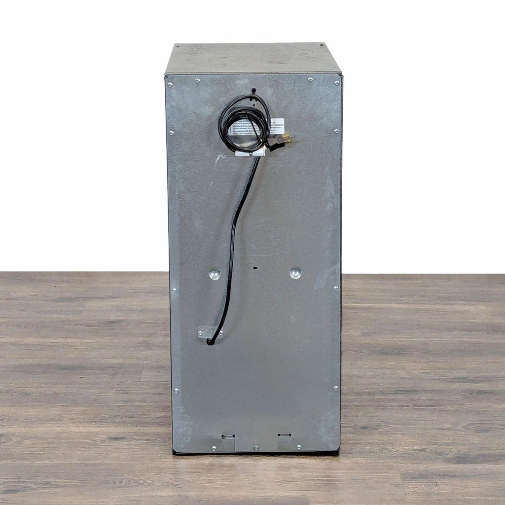 3. Rear view of the Gladiator trash compactor, showing its metal back and coiled power cord for workshop use.