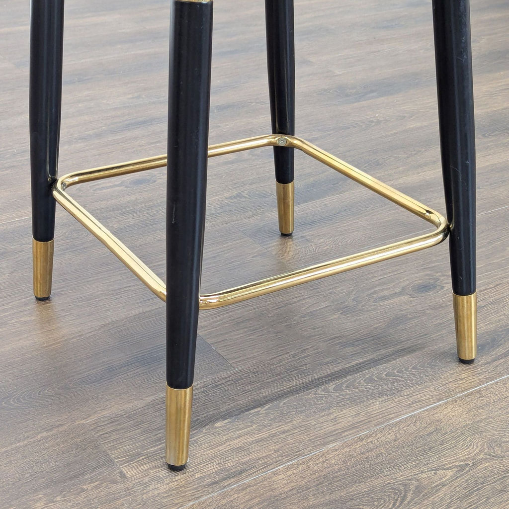 3. Detail view of the Reperch stool’s black legs and gold metal footrest, highlighting stylish finish and craftsmanship.