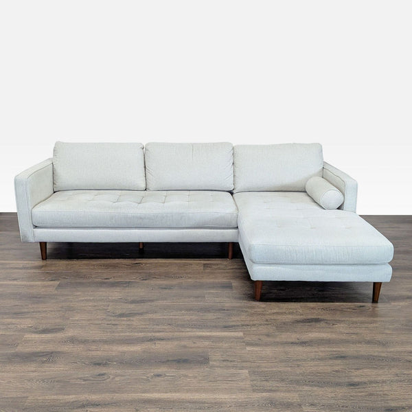 1. Living Spaces sectional sofa with light gray upholstery, chaise lounge, tufted cushions, and wooden legs shown from front.