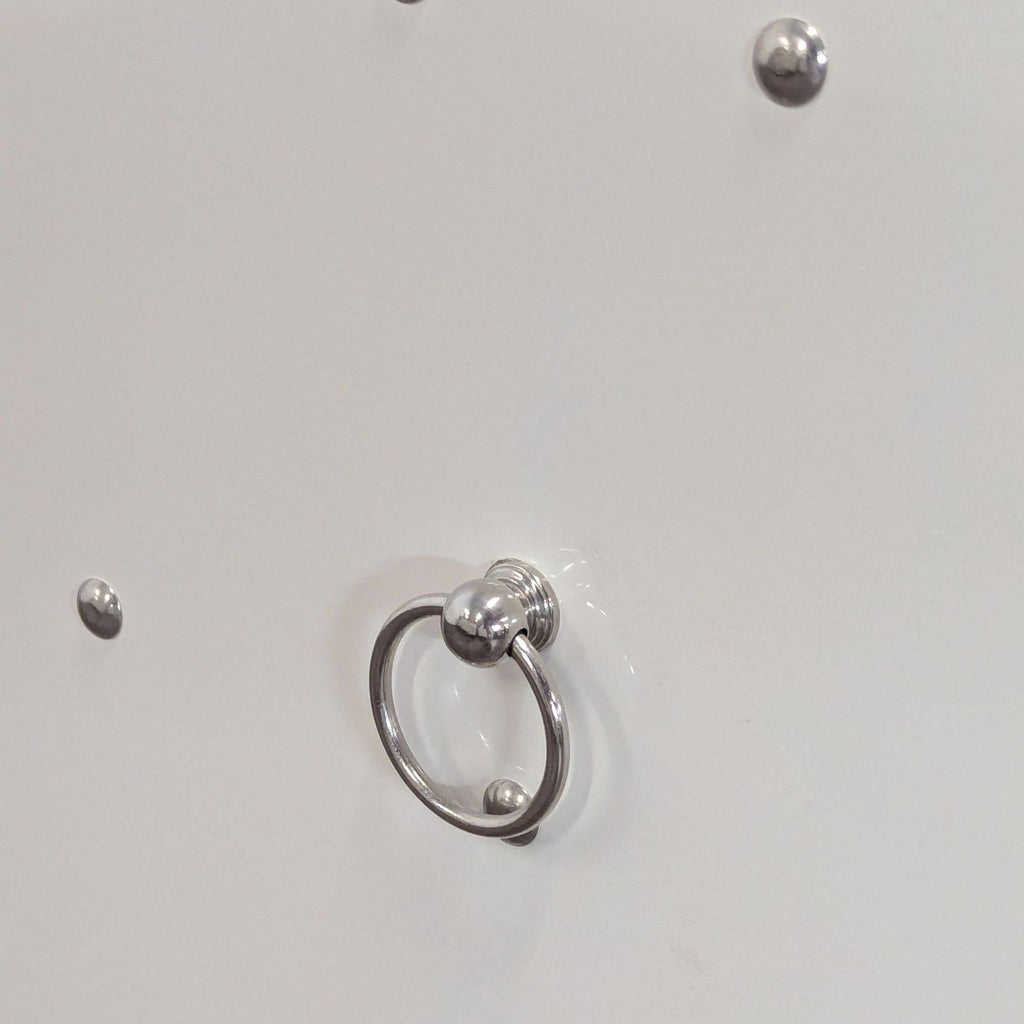 3. Silver round handle and decorative studs on a glossy white Reperch sideboard door.