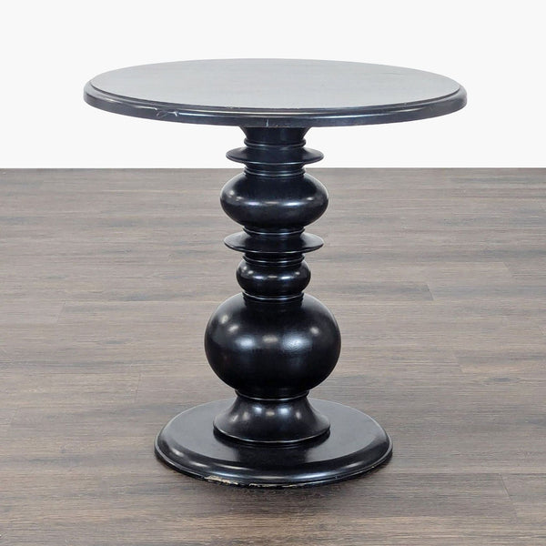 1. Black Reperch end table with a round top and ornate turned pedestal base, shown on a wood floor.  